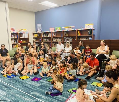 Story time children sitting on the floor listening to storytellers